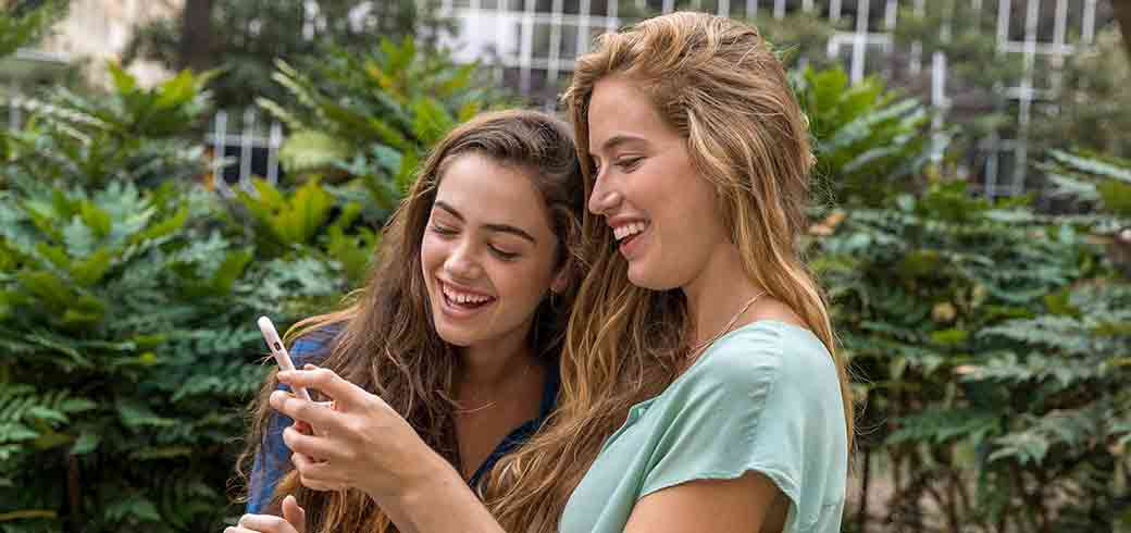 Hình ảnh của 2 người phụ nữ trẻ đang nhìn vào điện thoại trên đường phố