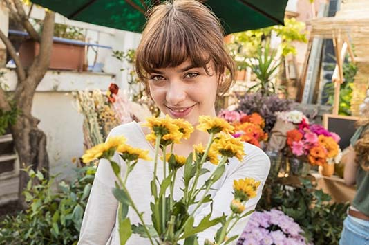 Hình ảnh một cô gái ở chợ nông sản, cầm bó hoa và nhìn vào máy quay